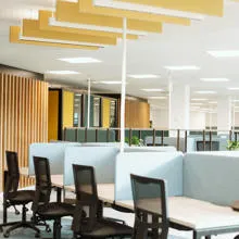 Study desks in the foreground with study pods with yellow walls in the background.