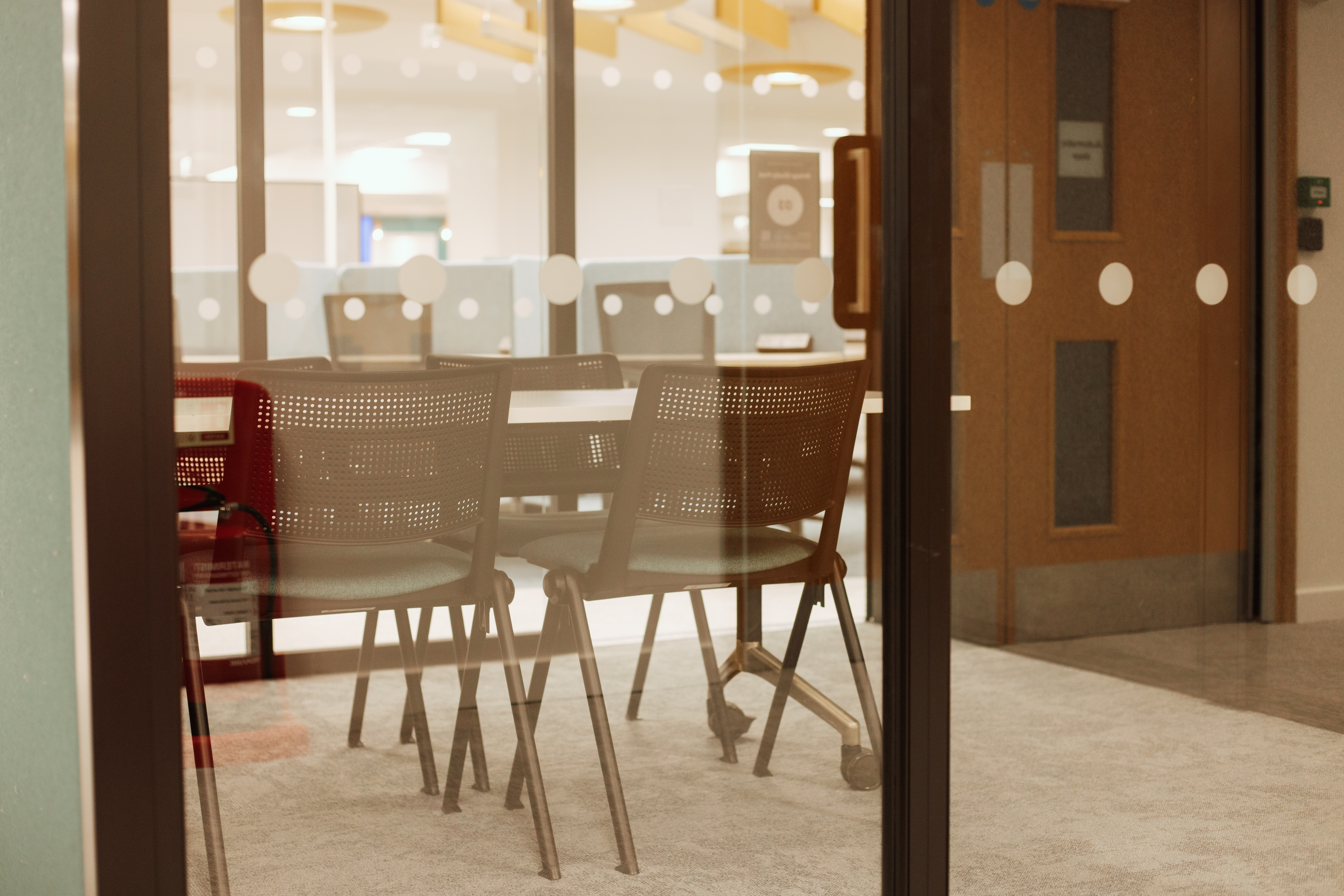 Close up view of table and chairs within group study pod with fire exit in background.