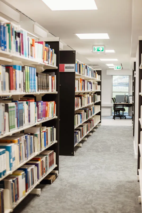 Rows of books with study spaces in the background.