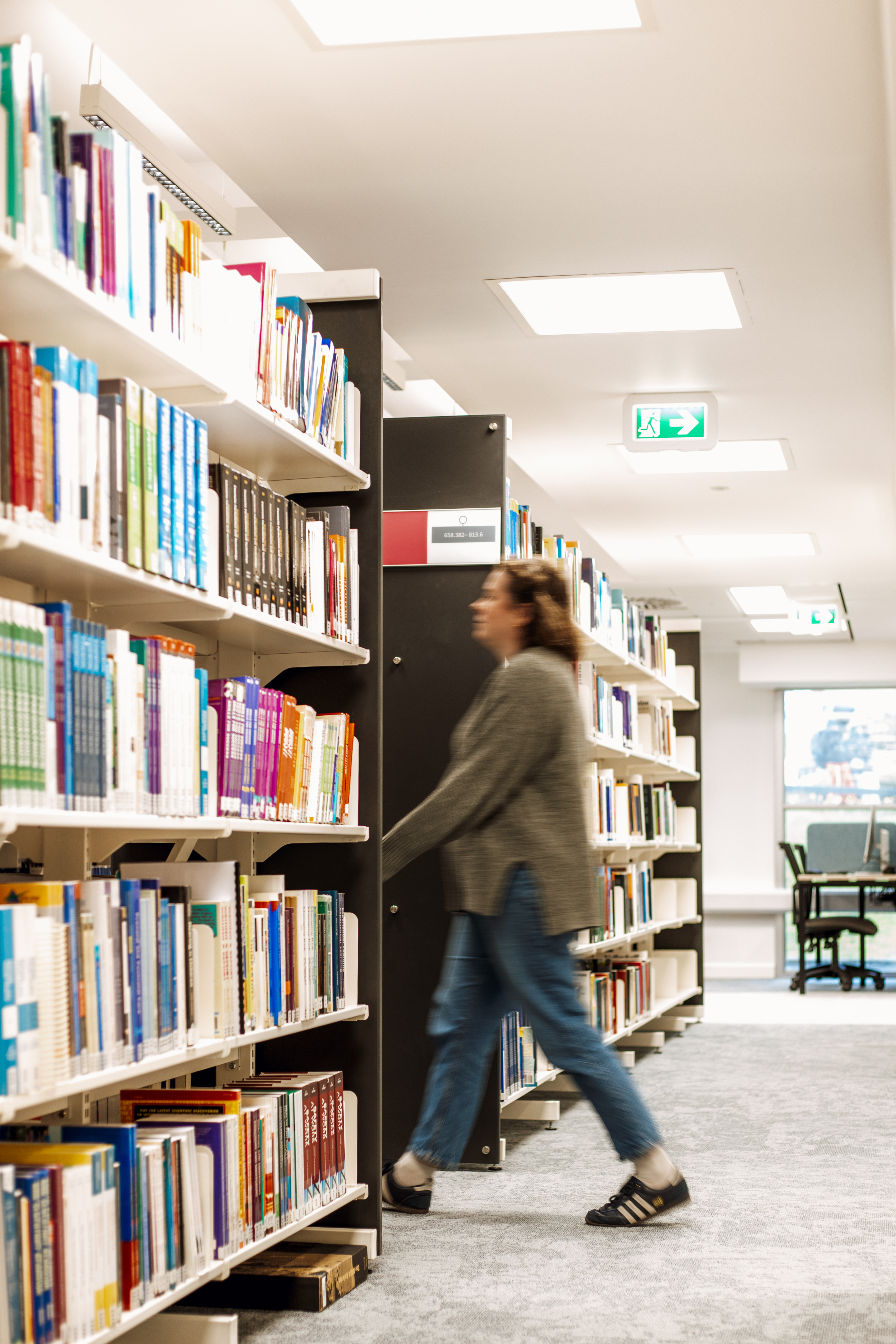 Blurred student walking between two rows of books.