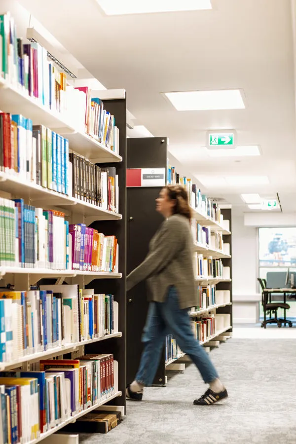 Blurred student walking between two rows of books.