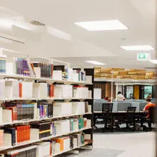 Shelves of books on the left and students studying on the right.