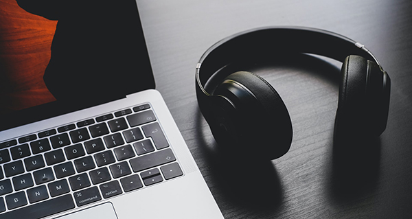 Laptop on a table next to headphones.